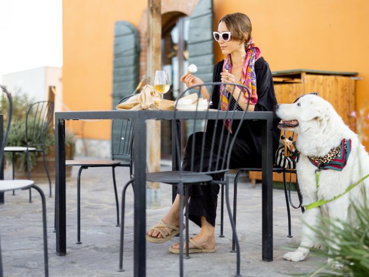 Woman Eating At An Outdoor Restaurant With A Dog